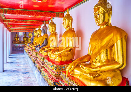 BANGKOK, THAILAND - 22. APRIL 2019: Die Linie der goldenen Statuen des Buddha in überdachten Galerie von Phra Rabiang Kloster Wat Pho temle, am 2. April Stockfoto