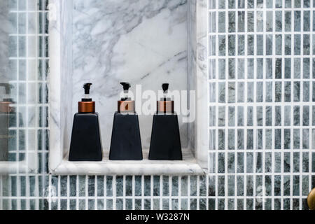 Pflegeprodukte im Badezimmer auf Marmor Regal. Grau Blau Mosaik Fliese. Minimalismus Konzept Stockfoto