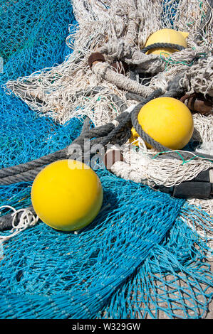 Hell Blau und Gelb Fischernetze und Bojen auf Harbourside Stockfoto