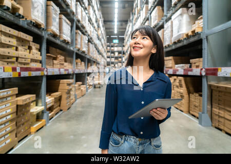Junge asiatische Frau Prüfer oder Trainee Personal Arbeit suchen und prüft die Anzahl der Elemente speichern von digitalen Tablet. Asiatische Eigentümer oder Small Business conce Stockfoto