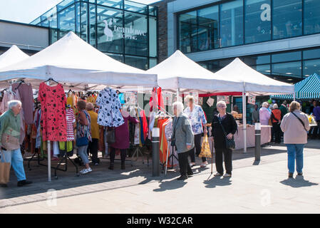 Käufer, um Marktstände mit Kleidung und Lebensmitteln am Markttag in Poulton gefüllt le Fylde Lancashire England Großbritannien Stockfoto