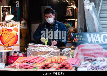 Tokyo, Japan - 30. März 2019: aufgespießt Wagyu Beef, Seeigel Kaviar auf Spieße in Tsukiji-fischmarkt von Ginza mit Mann Anbieter kochen grillein Stockfoto