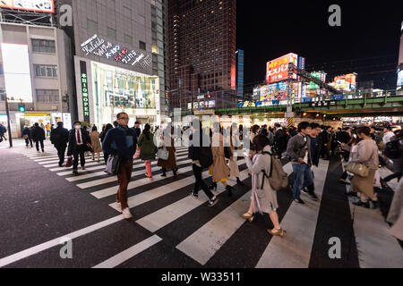 Shinjuku, Japan - April 4, 2019: Seitenansicht des überqueren Zebrastreifen in der Innenstadt von Tokyo City mit Neonleuchten, kommerzielle Werbung in der Nacht Stockfoto