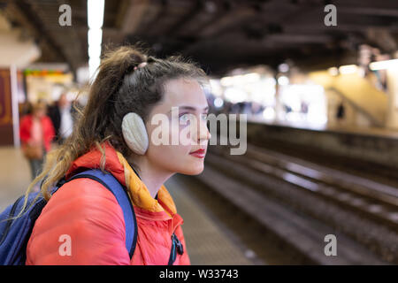 Junge Frau wartet auf Utsunomiya JR Japan Rail Bahnhof Plattform mit Eisenbahn Schienen, Menschen in verschwommenen Hintergrund Stockfoto