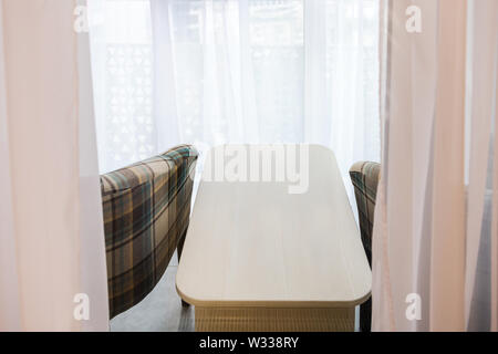 2 Sessel und kleiner Tisch im neuen Haus auf überdachten Balkon in Staging Modell Haus oder Apartment mit weißen Gardinen Jalousien Stockfoto