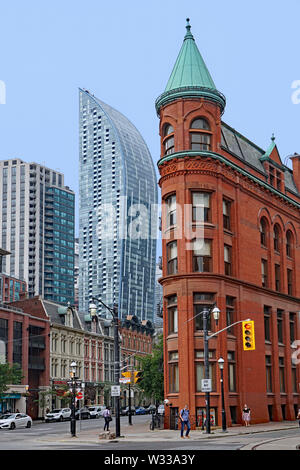 TORONTO - Juli 2019: viktorianischen Gebäude, darunter die Gooderham Flatiron und Gusseisen Gebäude, mit modernen Wolkenkratzern im Hintergrund. Stockfoto