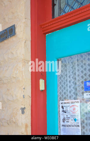 Eine alte Glastür vorn mit Gardinen im Südwesten von Farben, mit Plakaten die Förderung humanitärer Stimmung und Aktivist in Bisbee, AZ Stockfoto