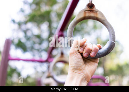 Nahaufnahme der männlichen Hand tun Pull Ups auf Ringe in farbenfrohen Spielplatz Park im Sommer mit bokeh Hintergrund Stockfoto