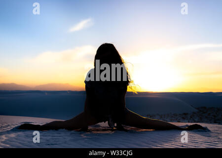 Frau silhouette Trainieren tun Splits Übung in White Sands Dunes National Monument in New Mexico Sonnenuntergang Stockfoto