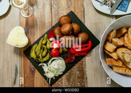 Vorspeisen Vorspeisen sweet cherry mini Paprika gefüllt mit weichem Käse Feta und Zwiebeln auf schiefer Platte. Stockfoto