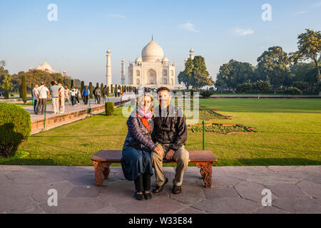 Eine westliche Paar sitzt für ein Foto vor dem Taj Mahal in Agra, Uttar Pradesh, Indien posieren.