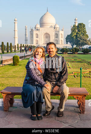 Eine westliche Paar sitzt für ein Foto vor dem Taj Mahal in Agra, Uttar Pradesh, Indien posieren.