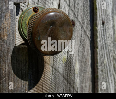 Getragen und glänzendes Metall Knopf mit grünem Korrosion auf einem alten Schuppen. Stockfoto