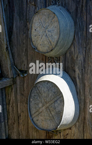 Zwei Zinn Bäder für Erwachsene und Kinder hängen auf einer Hütte an der Wand. Stockfoto