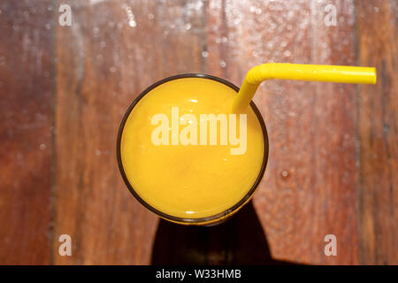 Mango Smoothie in einem Glas auf Holz- Hintergrund. Gelbe mango schütteln. Tropische Früchte Konzept. Ansicht von oben, in der Nähe Stockfoto