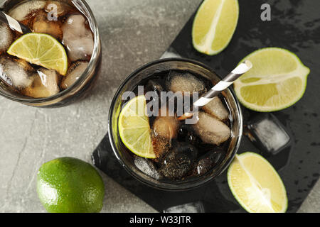 Gläser mit kalten Cola und Zitrusfrüchten auf grau Tabelle, Ansicht von oben Stockfoto