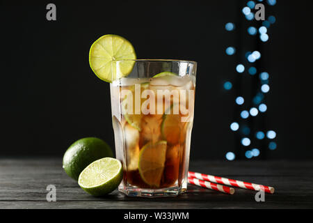Glas kalten Cola mit Zitrusfrüchten und Eis auf hölzernen Tisch gegen den dunklen Hintergrund Stockfoto