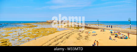 Die Menschen genießen Sie ein Sonnenbad in La Caleta Strand mit dem San Sebastian Castle, eine Festung in La Caleta Insel, im Hintergrund. Cadiz. Spanien Stockfoto
