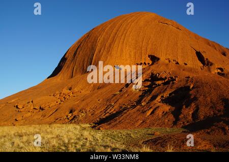 Am frühen Morgen Sonne Beleuchtung eines Uluru Felsformation Stockfoto