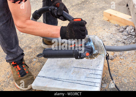 Der Arbeiter verwendet eine Diamant-trennscheibe und ein Winkelschleifer die Pflasterung bar und Blech zu schneiden. Stockfoto