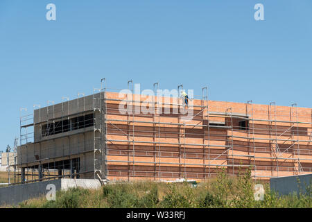 Gebäude Baustelle mit Gerüsten und Unerkennbare Arbeiter auf das Dach springen. Platz kopieren Stockfoto