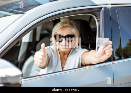 Portrait Of Happy Senior Frau, Führerschein, beim Sitzen im Auto. Konzept einer aktiven Personen im Rentenalter Stockfoto