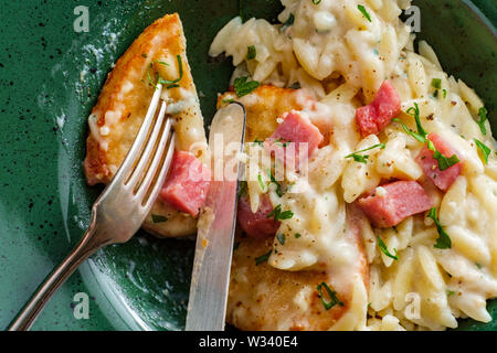 Hähnchen Cordon bleu mit cremiger orzo Risotto und Schinken serviert. Stockfoto