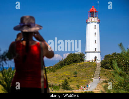 11 Juli 2019, Mecklenburg-Vorpommern, Kloster: ein Urlauber mit einem Stroh Hut Fotos der Leuchtturm auf der Ostseeinsel Hiddensee. Der Leuchtturm wurde in 1887/1888 als Backsteinbau errichtet, hat eine Höhe von 27,5 m und einer Höhe von 94,7 m über Nn auf die Ostsee. Tausende Urlauber und Tagesgäste sind täglich auf der Insel in den Sommermonaten gezählt. Hiddensee ist weitgehend autofrei und Pferd und Wagen ist ein weit verbreitetes Transportmittel. Hiddensee ist ca. 16,8 Kilometer lang, an ihrer schmalsten Stelle etwa 250 Meter breit und am breitesten etwa 3 Stockfoto