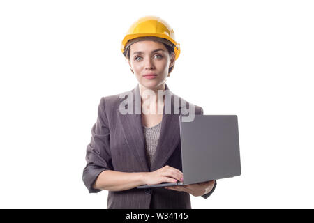 Portrait von Happy Business Engineer Frau im gelben Helm auf dem Kopf stehend und mit Laptop. Stockfoto