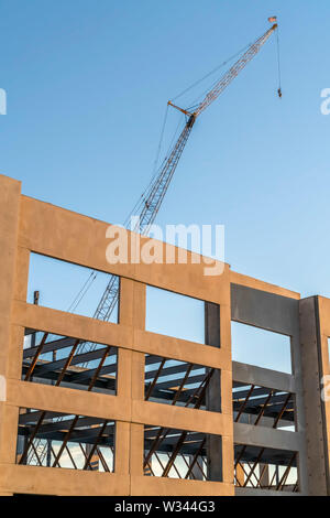 Gebäude im Bau mit Metall Kran und blauer Himmel. Der Innenraum Metall Rahmen kann durch die quadratische Fenster Löcher gesehen werden. Stockfoto