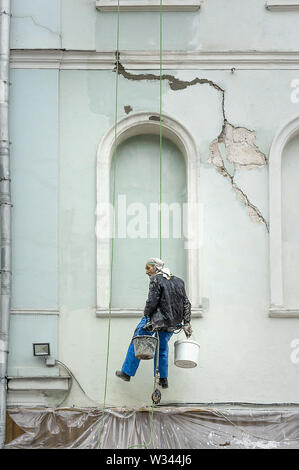 Moskau, Russland - Oktober 29, 2018: Alte Arbeitnehmer hängen an einem einzigen Seil Linie, die Vorbereitung der Wand eines alten Gebäudes zu lackieren. Stockfoto