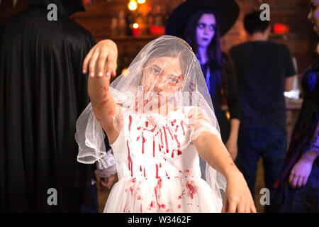 Portrait von kleinen Mädchen gekleidet wie eine Braut mit Blut an Halloween Party abgedeckt. Mädchen mit creepy Ausdruck. Stockfoto