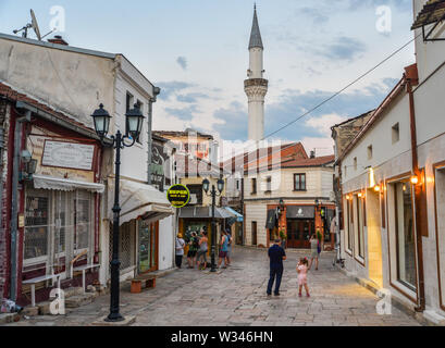 SKOPJE, MAZEDONIEN - 22. AUGUST 2019: Fußgänger und Anwohner schlendern und Kneipe, am frühen Abend, in der Nähe einer Moschee, die Straßen des Alten Basar, Skopje Stockfoto