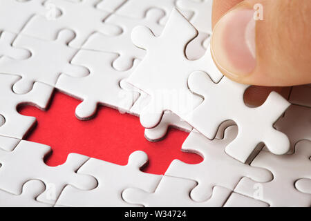 Hand das letzte Stück des Puzzles zur Vollendung der Aufgabe Stockfoto