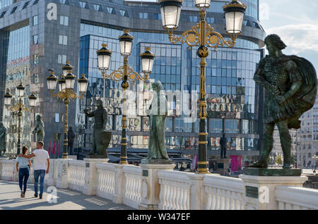 SKOPJE, MAZEDONIEN - 23. AUGUST 2019: ein paar Gehminuten umarmte, vorbei an prunkvollen Statuen, über eine Brücke in Richtung Mazedonien Square führt. Stockfoto