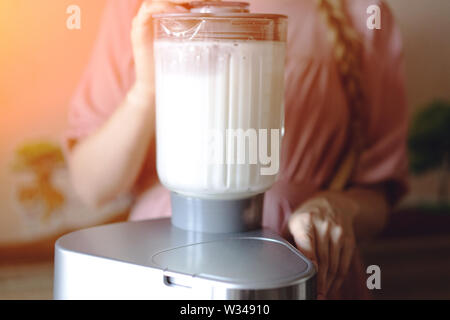 Frau, die Kokosmilch in einen Mixer Stockfoto