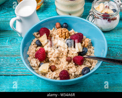 Schüssel Müsli mit Himbeeren und Blaubeeren auf einem blauen Holztisch. Stockfoto