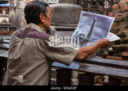 Mann stand durch einen Tempel eine Zeitung lesen Artikel über die Rato Machhindranath Jatra Festival in Kathmandu Stockfoto