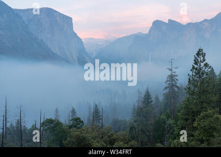 Klassischer Tunnel Blick auf das malerische Yosemite Valley mit dem berühmten El Capitan und Half Dome klettern Gipfel in schönen nebligen Atmosphäre am Morgen Stockfoto