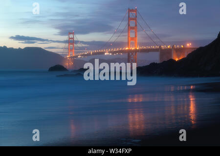 Klassischer Panoramablick auf die berühmte Golden Gate Bridge von der aus gesehen Landschaftlich schöner Baker Beach in schönen goldenen Abendlicht auf einem Sonnenuntergang mit blauem Himmel und Wolke Stockfoto