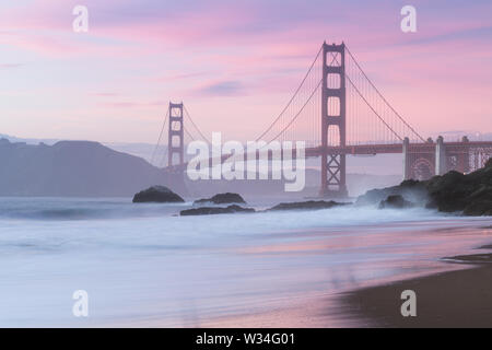 Klassischer Panoramablick auf die berühmte Golden Gate Bridge von der aus gesehen Landschaftlich schöner Baker Beach in schönen goldenen Abendlicht auf einem Sonnenuntergang mit blauem Himmel und Wolke Stockfoto
