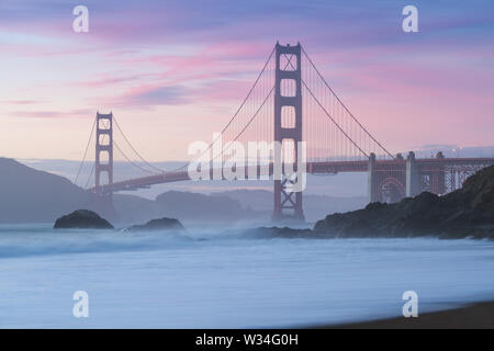 Klassischer Panoramablick auf die berühmte Golden Gate Bridge von der aus gesehen Landschaftlich schöner Baker Beach in schönen goldenen Abendlicht auf einem Sonnenuntergang mit blauem Himmel und Wolke Stockfoto