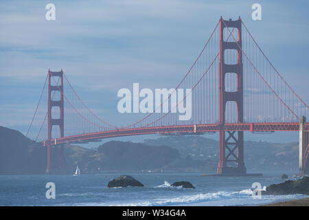 Klassischer Panoramablick auf die berühmte Golden Gate Bridge von der aus gesehen Landschaftlich schöner Baker Beach in schönen goldenen Abendlicht auf einem Sonnenuntergang mit blauem Himmel und Wolke Stockfoto