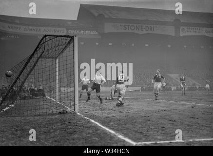 England Mitte - halber Nat Lofthouse (weißes Hemd, nächste Kamera) und Liga Irlands voll-zurück-M.Burke (Nr. 2) Sehen Sie sich die Kugel geben Sie das Netz für ein Ziel. Irland Torhüter D. Barrett ist unten auf einem Knie. Das gleiche wie bei Maine Road in Manchester statt. Stockfoto