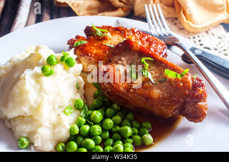 Honig Marmelade verglaste BBQ Schweinekoteletts mit Kartoffelpüree und Erbsen Stockfoto