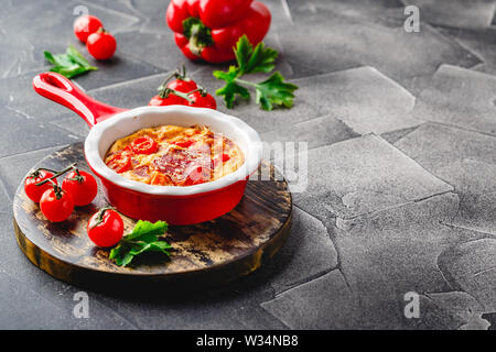 Frittata mit Paprika, Tomaten und Salami in Keramik Skillet. Art der italienische Omelette mit Gemüse. Stockfoto