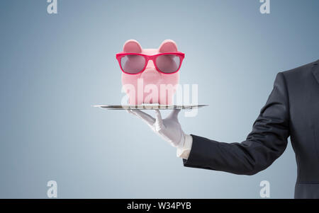 Geschäftsmann mit Sparschwein mit rosa Brille auf silbernem Tablett Stockfoto