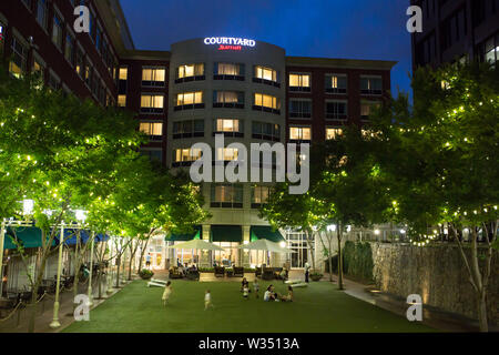 GREENVILLE, SC (USA) - Juli 5, 2019: Ein Nach-düstere Sicht auf die Downtown Marriott Courtyard Hotel mit Kindern spielen vor. Stockfoto