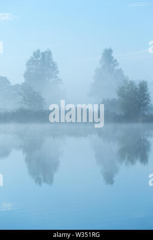 Ein ruhiger und ruhiger Morgen am Fluss mit Nebel im Herbst und ein schönes Spiegelbild im Wasser - Drentse Aa, Drenthe, Niederlande Stockfoto