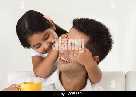 Mädchen, die ihren Vater die Augen von hinten bedeckt Stockfoto